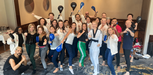 Executives from Benefit Cosmetics pose for a picture after participating in a Taekwondo experience.